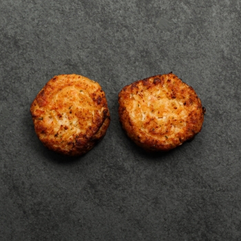 Overhead image of two cooked Lobster & Seafood cakes on a slate.