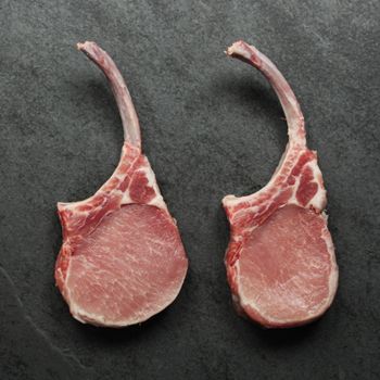 overhead view of two raw pork chop tomahawks with exposed frenched bones