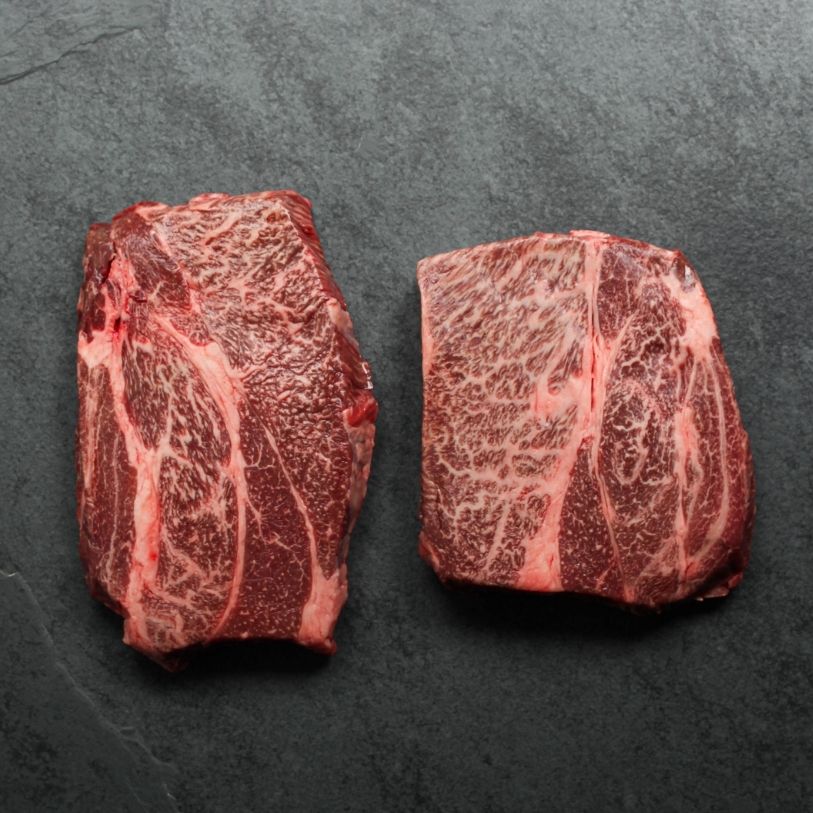 overhead view of two raw, heavily marbled chuck eye steaks