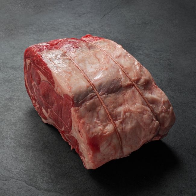 angled view of a raw beef capless prime rib roast, with the backbone removed and tied back on