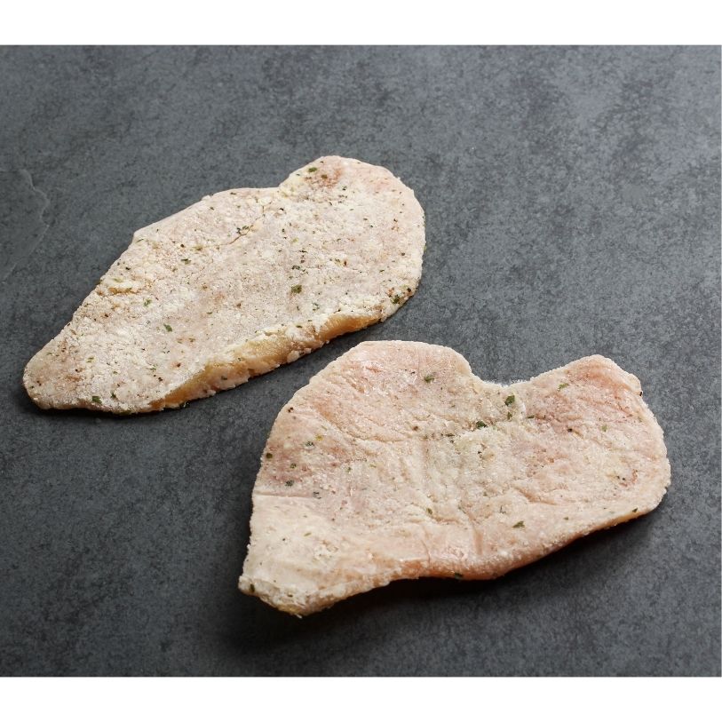 angled view of two, raw, lightly breaded chicken breast cutlets
