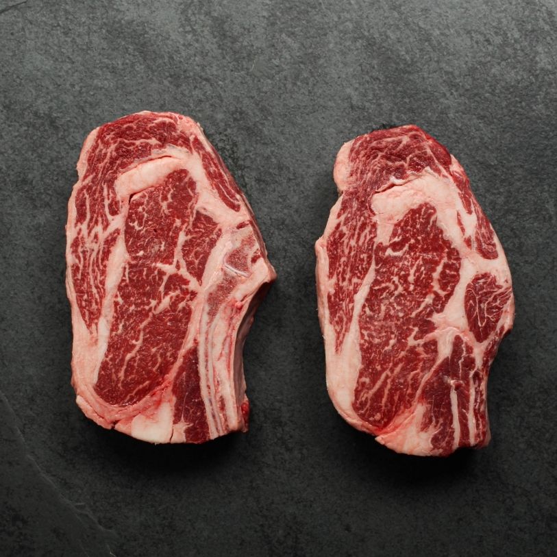 overhead view of two well-marbled bone-in, raw rib steaks