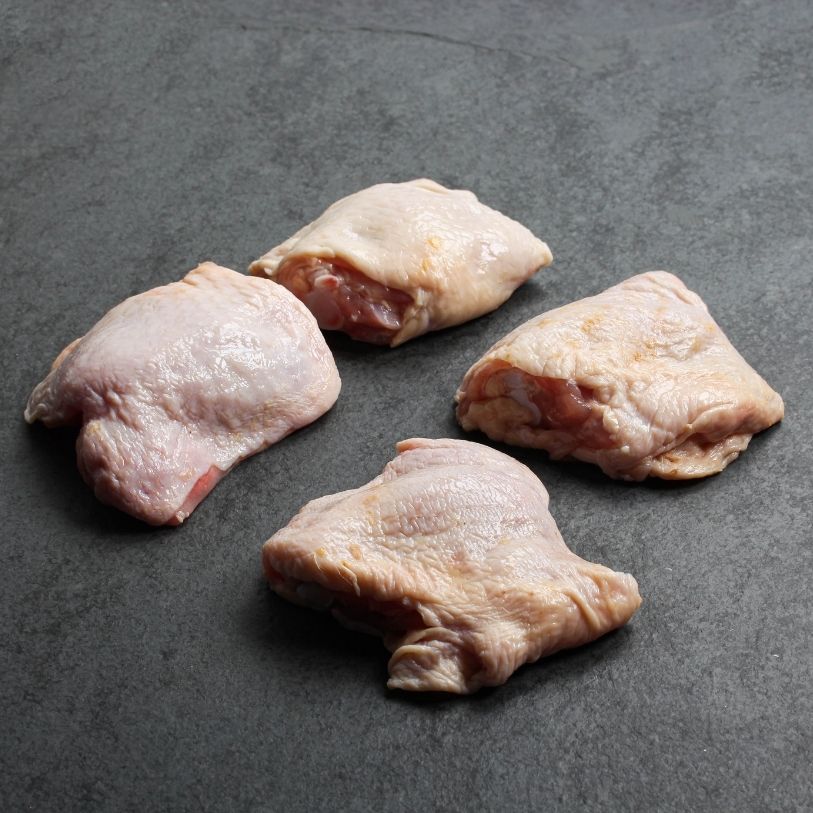 angled view of 4 raw bone-in, skin-on chicken thighs