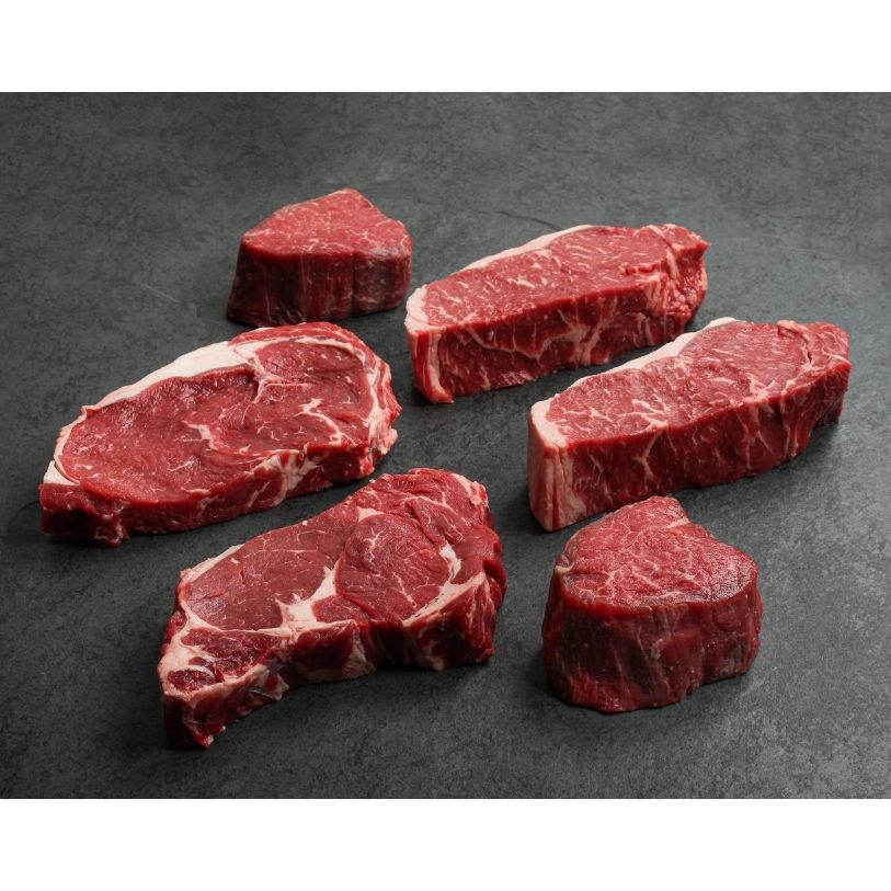 angled view of 2 raw rib eyes, 2 raw new york steaks, and 2 raw filet mignon's
