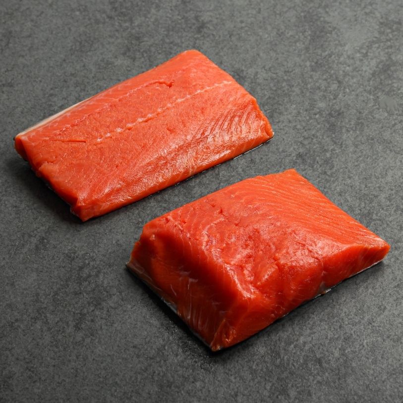 angled view of two raw, vibrant wild sockeye salmon portions