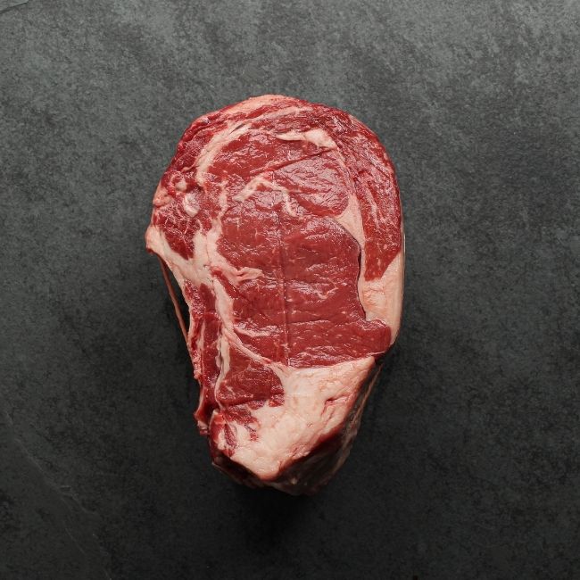 side view of a raw beef capless prime rib roast, with the backbone removed and tied back on