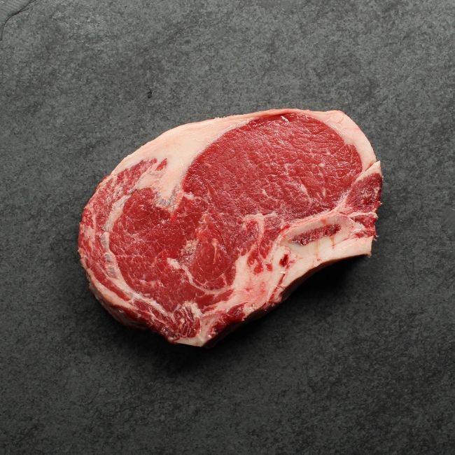 Bottom side of raw bone in rib steak.