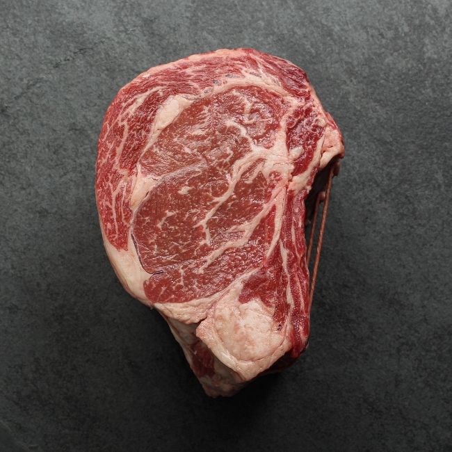 side view of a raw capless prime rib roast with the back bones removed and tied back on