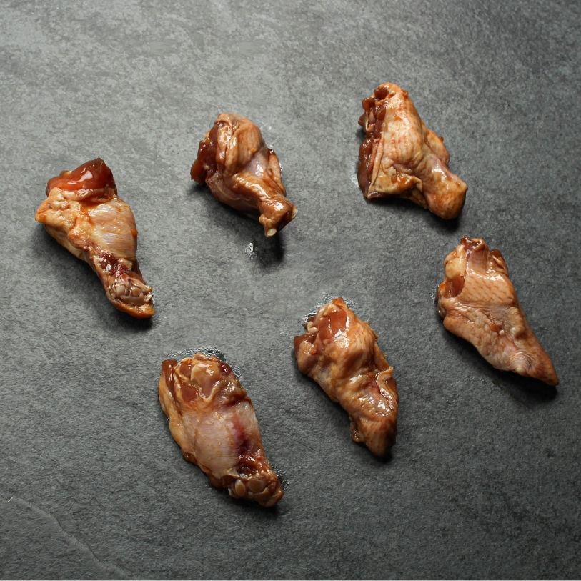 angled view of 6 raw, honey-garlic marinated chicken fryer drumettes
