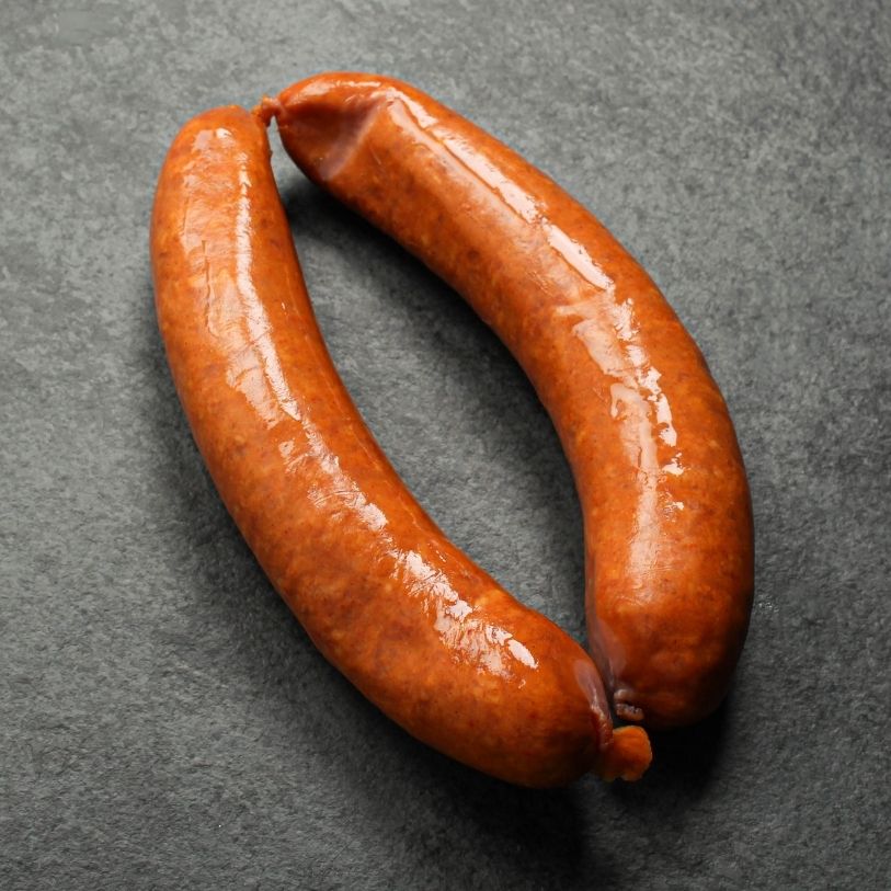 angled view of two, raw european style hot honey sausages
