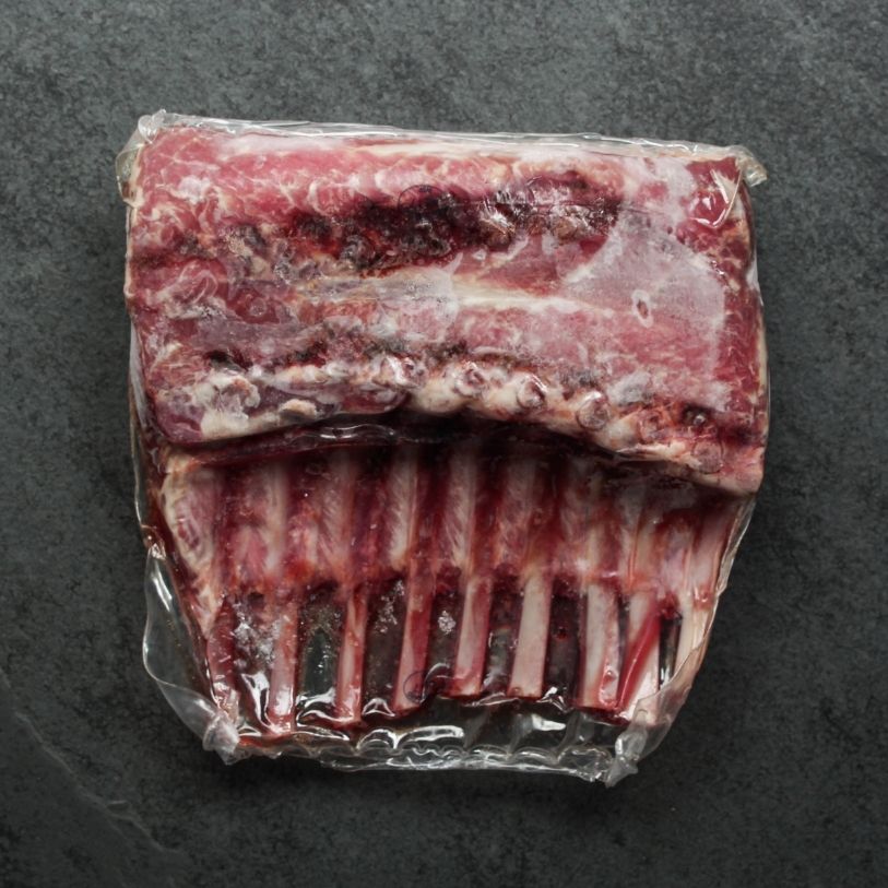 overhead shot of two raw, frenched lamb racks in vacuum packaging