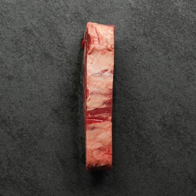 overhead view of the side of a raw, well-marbled grass fed ribeye steak