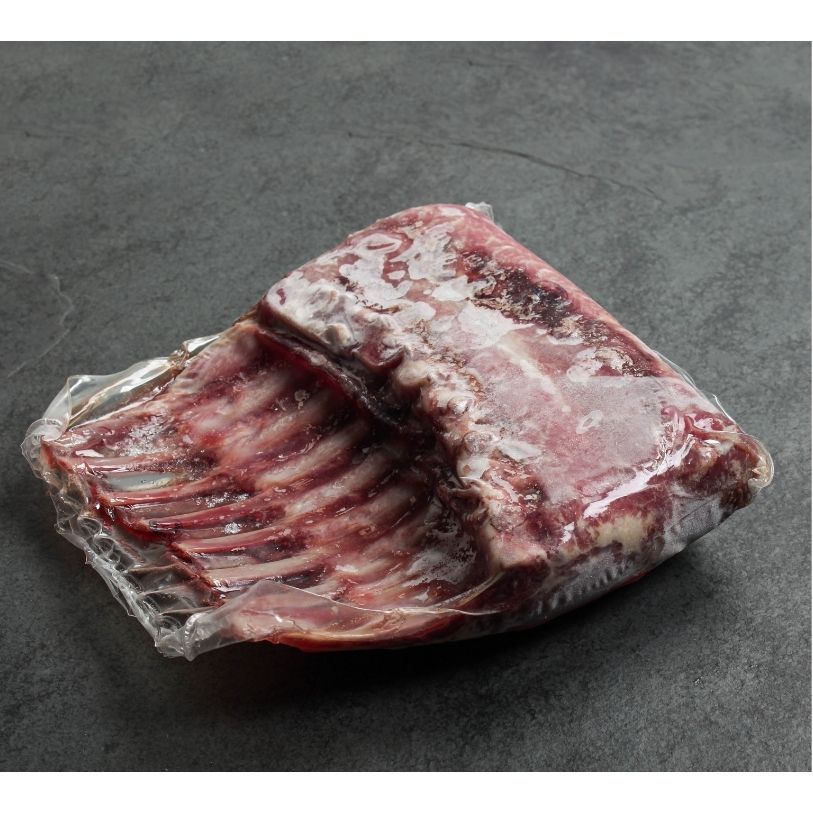 angled shot of two raw, frenched lamb racks in vacuum packaging