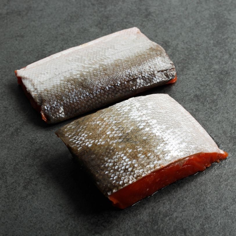 angled view of two raw, skin-side-up wild sockeye salmon portions