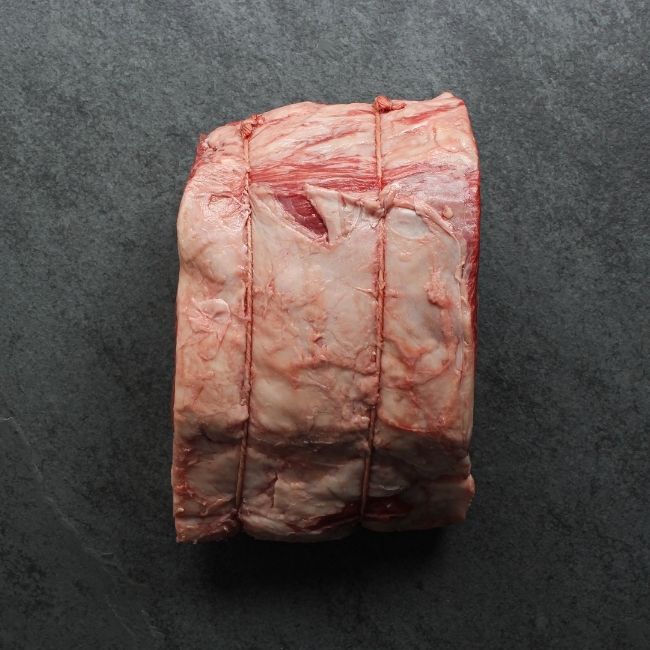 overhead view of a raw capless prime rib roast with the back bones removed and tied back on