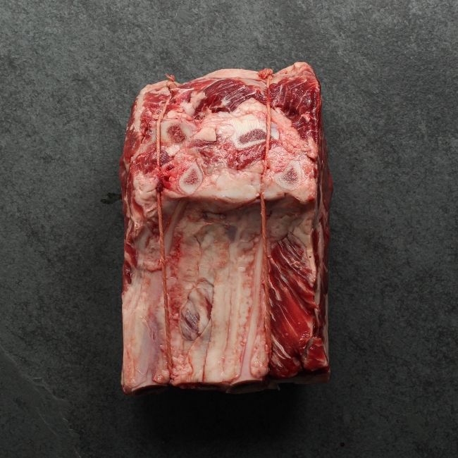 overhead view of a raw beef capless prime rib roast, with the backbone removed and tied back on