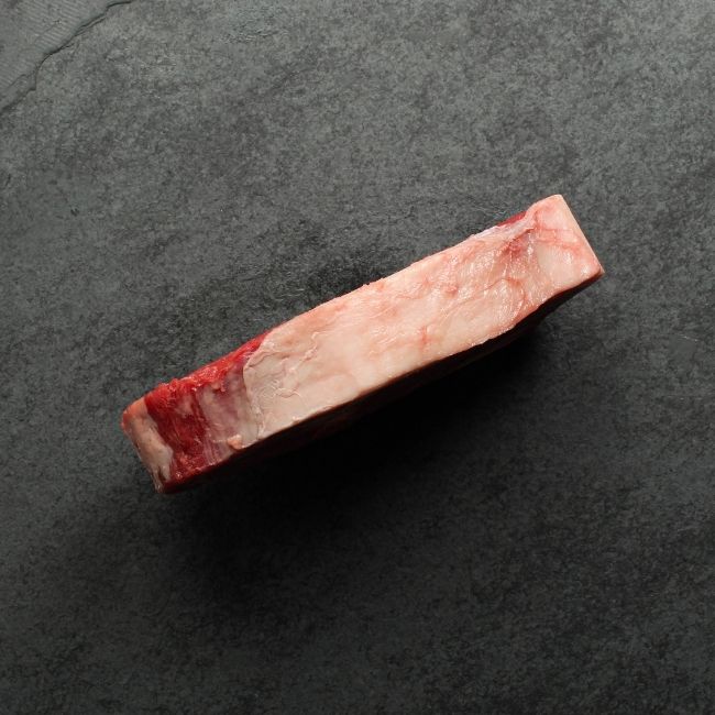 side view of raw bone in rib steak.