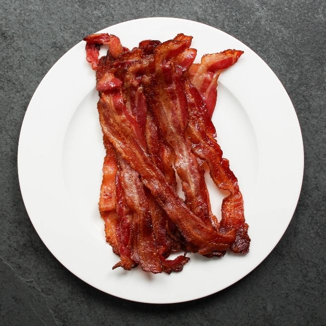 overhead view of cooked, crispy, sliced bacon on a plate