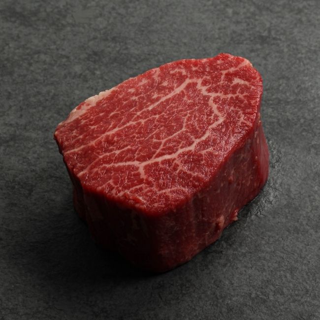 angled view of a raw heavily marbled American-wagyu beef hybrid filet mignon