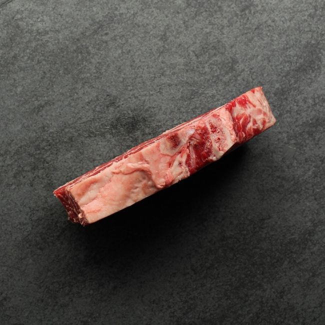 side view of raw bone in rib steak.