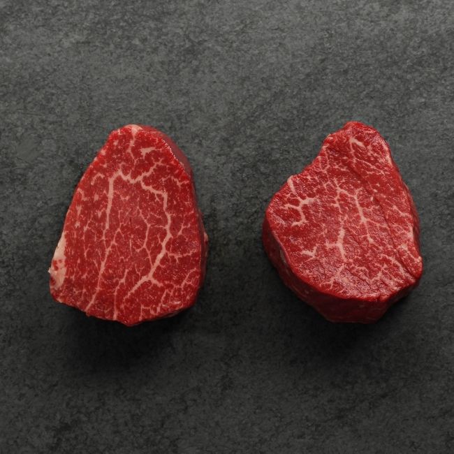 overhead view of two raw heavily marbled American-wagyu beef hybrid filet mignon steaks
